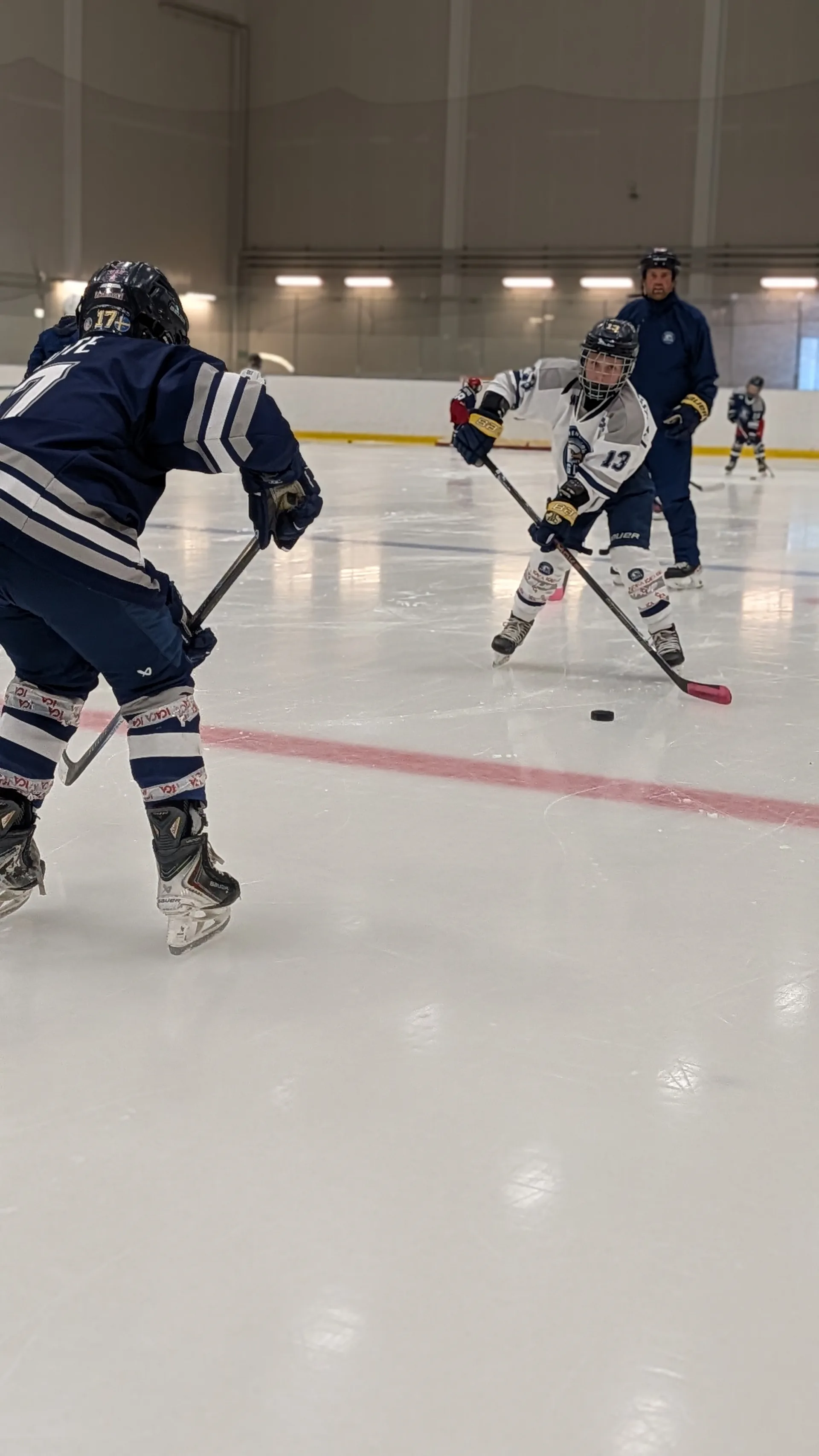 Två Eagles-spelare möts i en puckövning med en tränare bakom